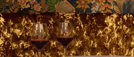 Dos copas de vino sobre una mesa, con una pared decorativa al fondo.