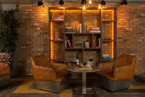 A cozy reading nook with leather chairs, a small table, and a brick wall bookshelf. - Nox Hotel (Galway)