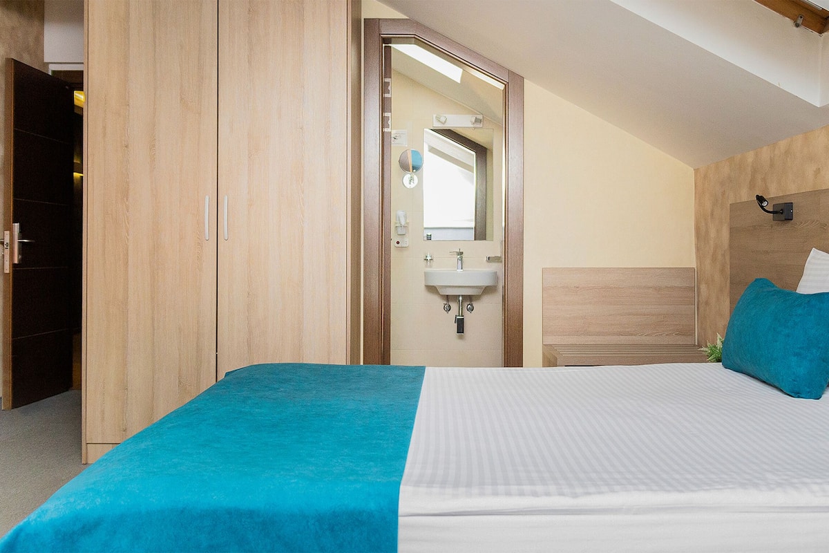 A bedroom with a bed, a nightstand, a mirror, and a wooden wardrobe.