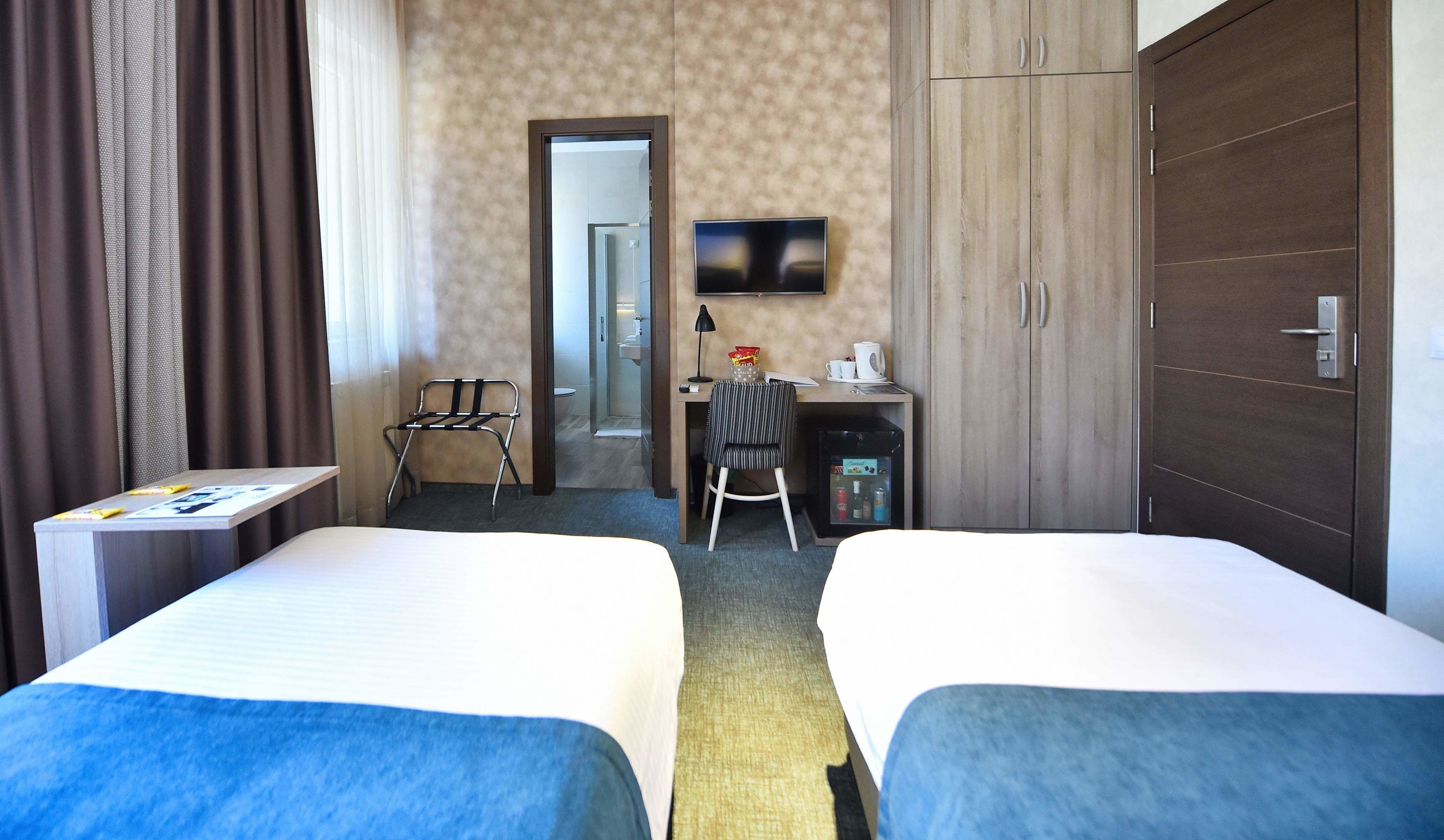 Ett hotellrum med två sängar, ett skrivbord med en stol, en tv och en garderob.
