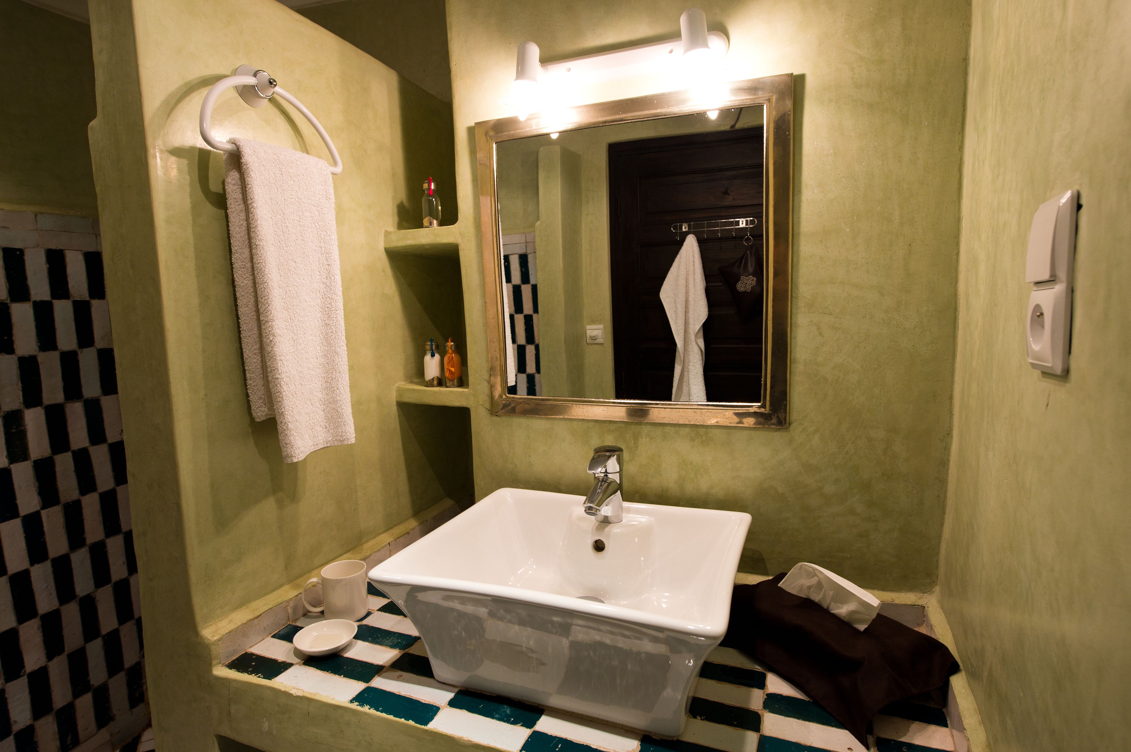 Une salle de bain avec un lavabo blanc, un miroir et un porte-serviettes.