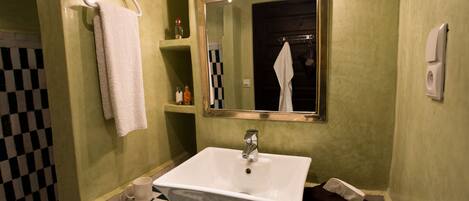 Une salle de bain avec un lavabo blanc, un miroir et un porte-serviettes.