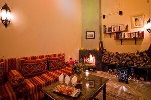 Un salón acogedor con un sofá, una chimenea, estanterías y un farol decorativo.