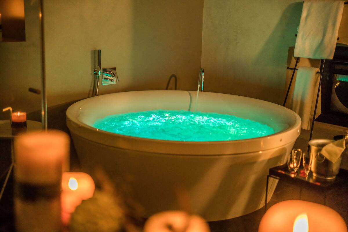 Une baignoire avec un élément décoratif aquatique bleu, un porte-serviettes et des bougies.