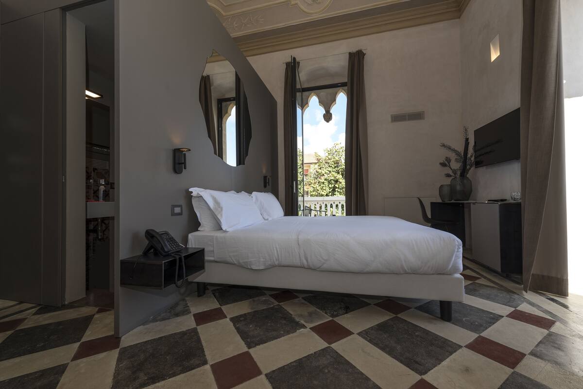 Une chambre d’hôtel moderne, dotée d’un grand lit, d’un bureau et offrant une vue sur l’extérieur.
