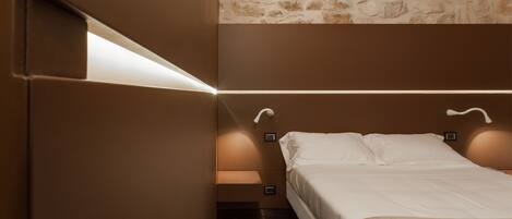 A bedroom with a bed, a stone wall, and built-in lighting.