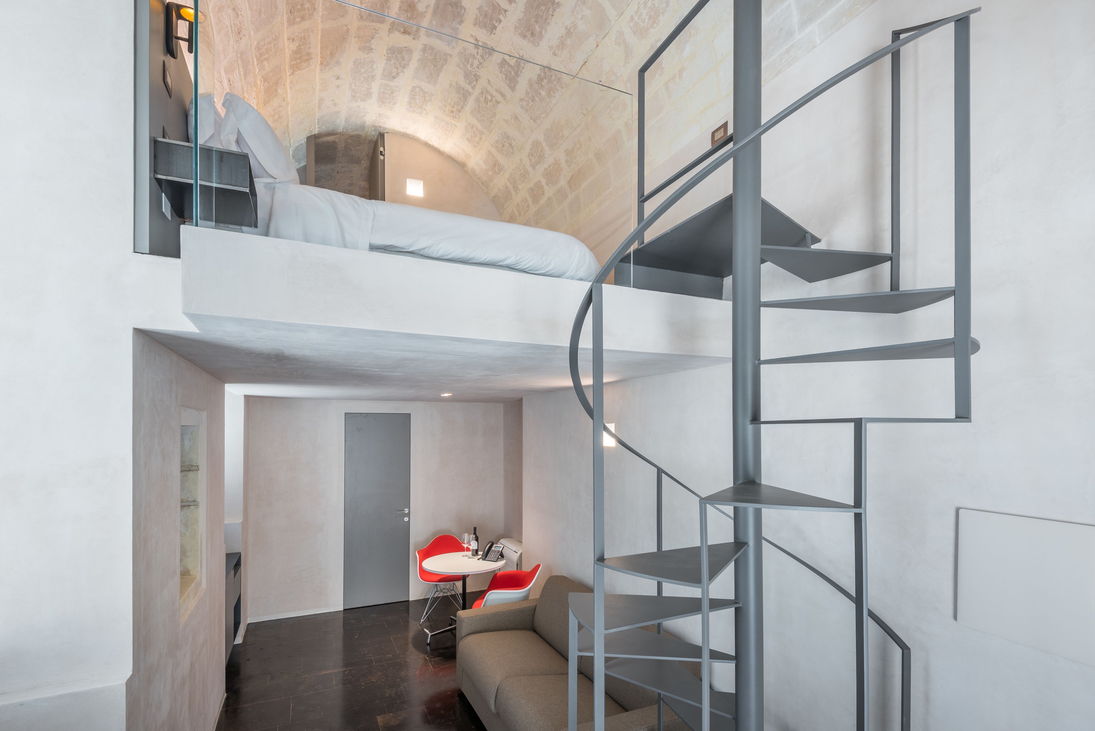 Ein modernes Schlafzimmer im Loft-Stil mit Etagenbett, Wendeltreppe und einer kleinen Sitzecke mit Tisch und Stühlen.