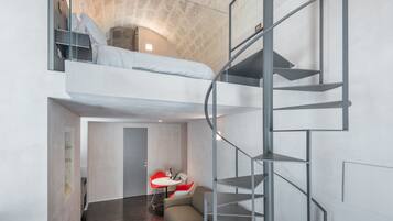 Ein modernes Schlafzimmer im Loft-Stil mit Etagenbett, Wendeltreppe und einer kleinen Sitzecke mit Tisch und Stühlen.