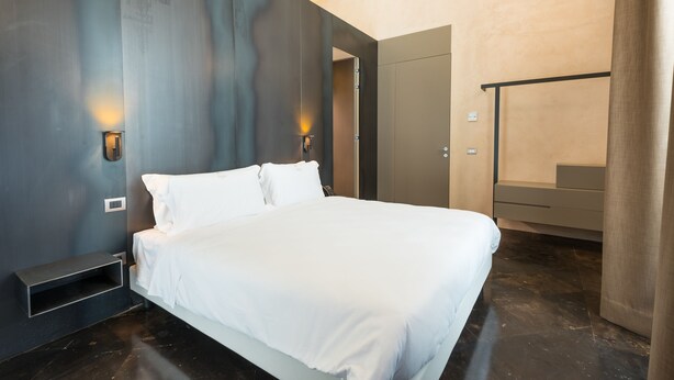 Une chambre moderne avec un grand lit, des tables de chevet intégrées et une armoire.