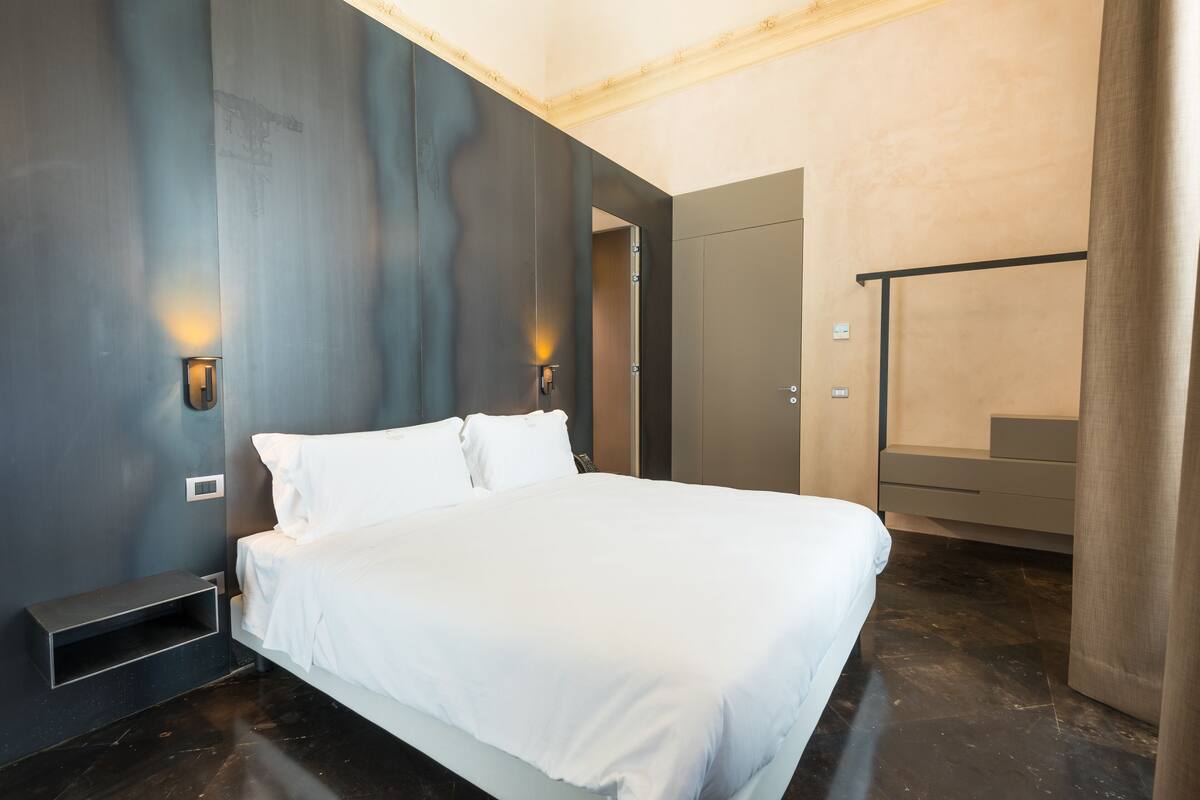 Une chambre moderne avec un grand lit, des tables de chevet intégrées et une armoire.
