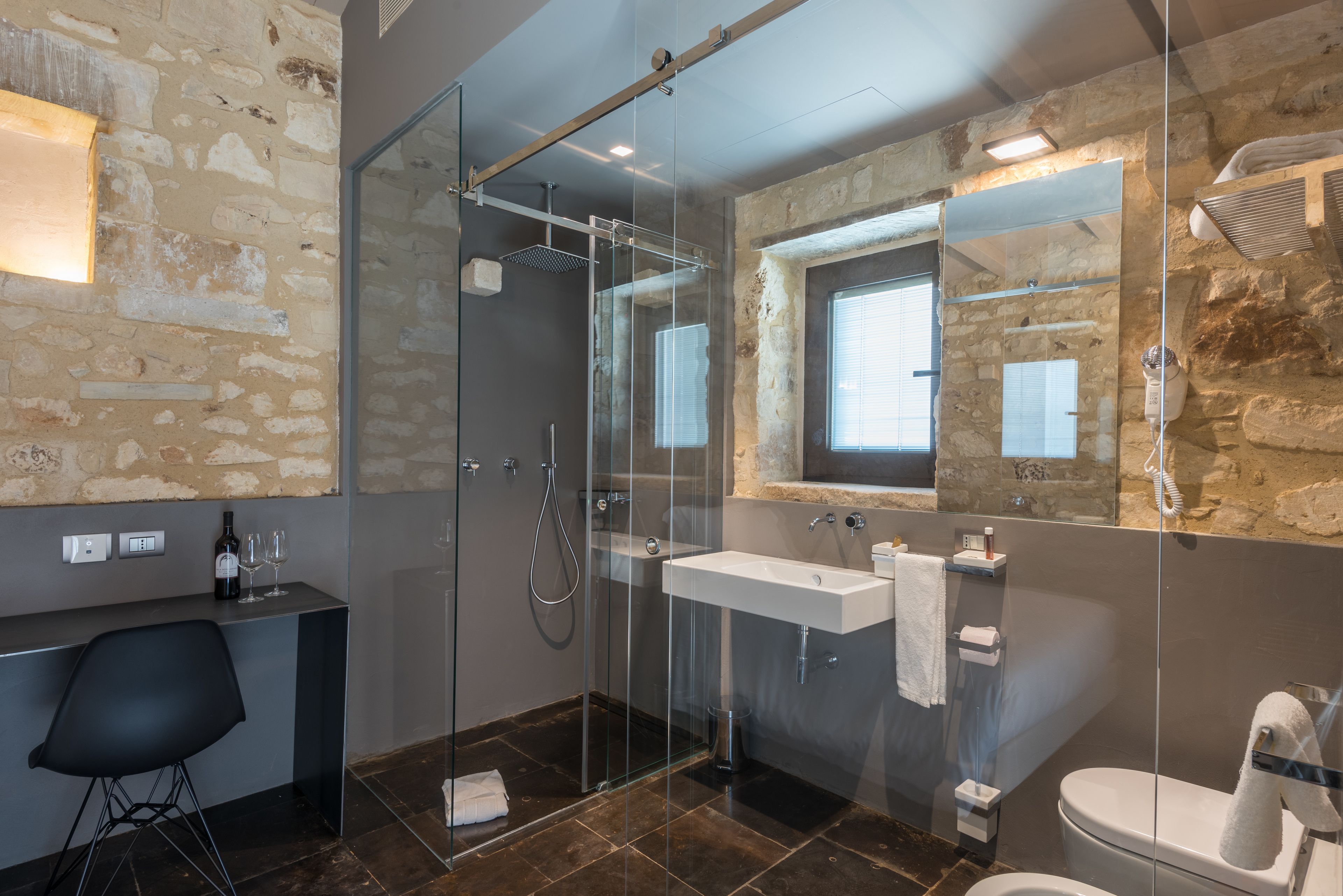 A modern bathroom with a glass-enclosed shower, a large mirror, a sink, and a toilet.
