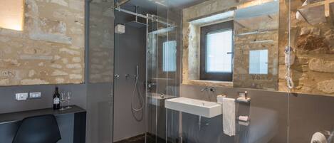 A modern bathroom with a glass-enclosed shower, a large mirror, a sink, and a toilet.