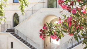 Un escalier de marbre menant à une porte en arc de cercle, entourée de fleurs roses.