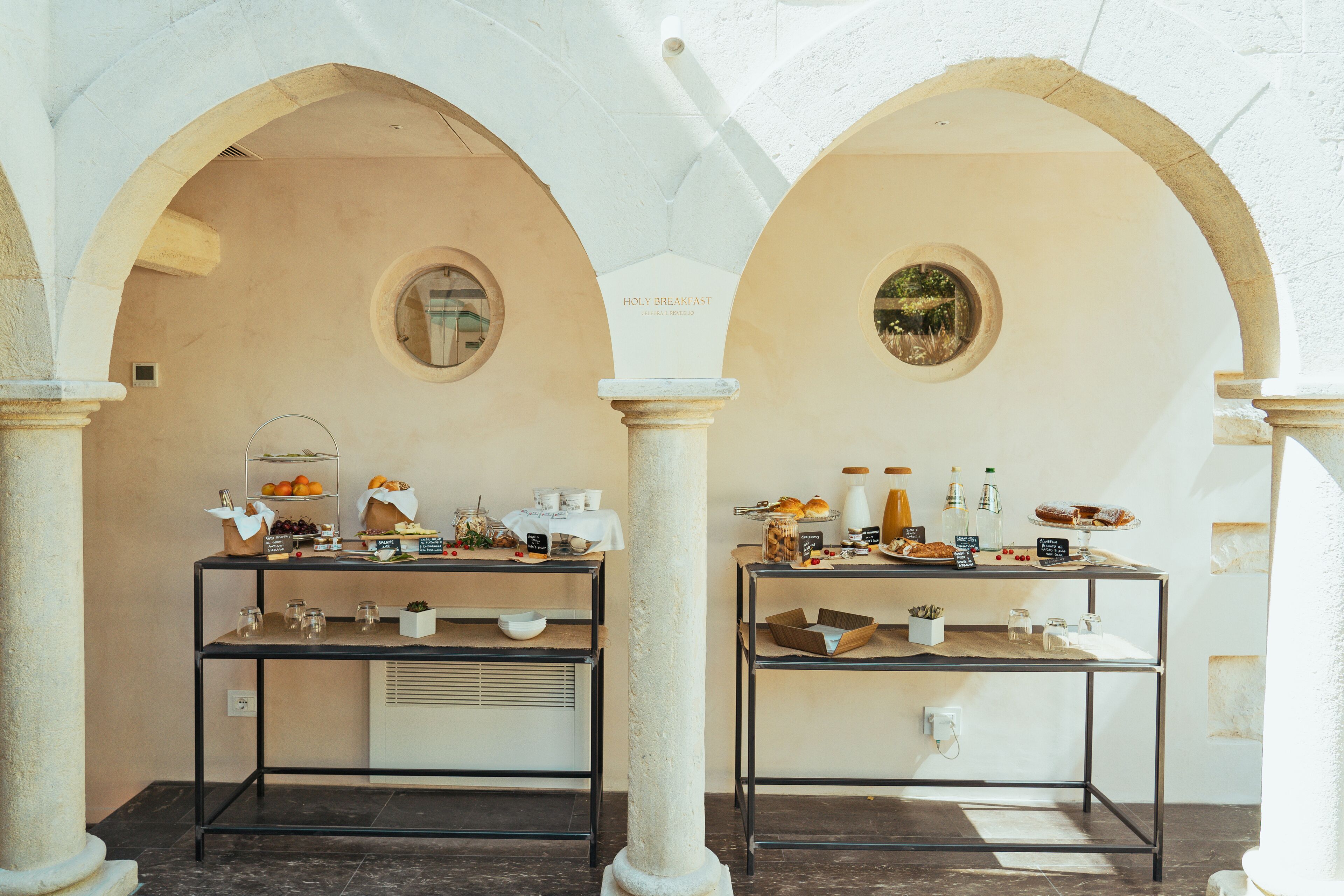 Una mesa de desayuno con dos mesas bajo arcos, mostrando diferentes alimentos y bebidas.