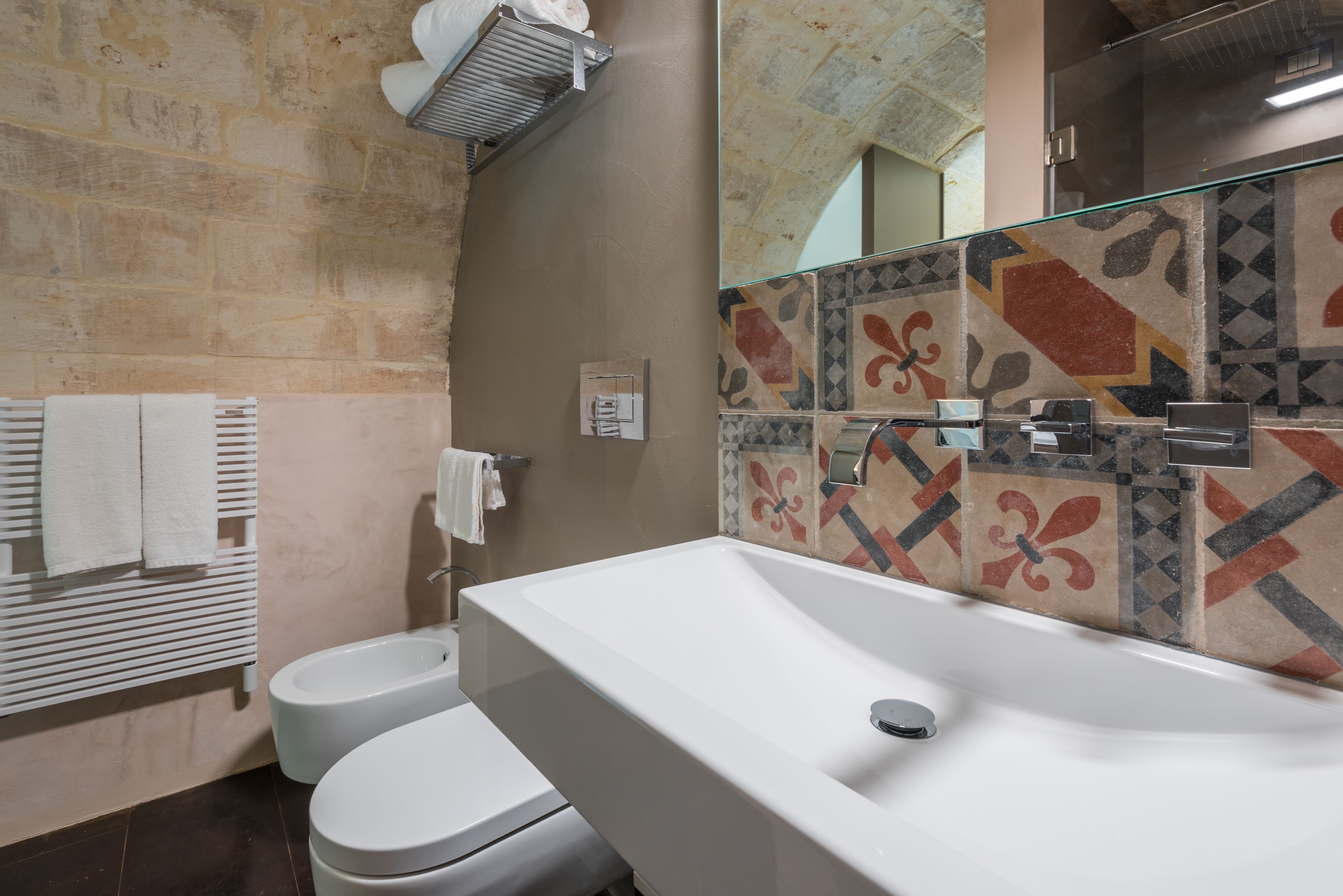 Un baño con lavamanos blanco, dos inodoros y zona de ducha.
