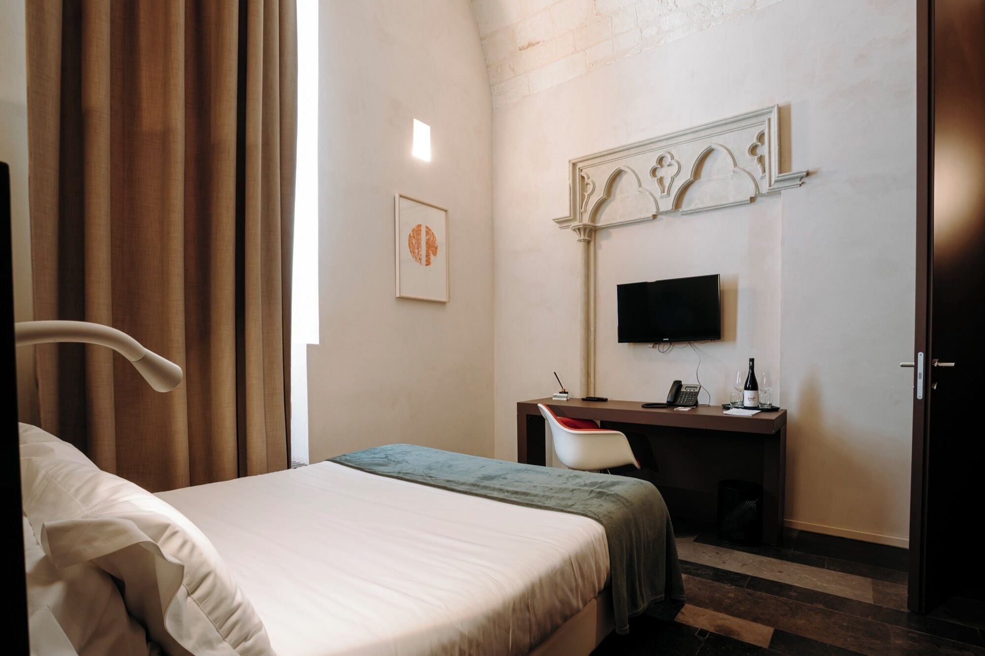 Une chambre d’hôtel avec un lit, un bureau, une télévision et une porte.