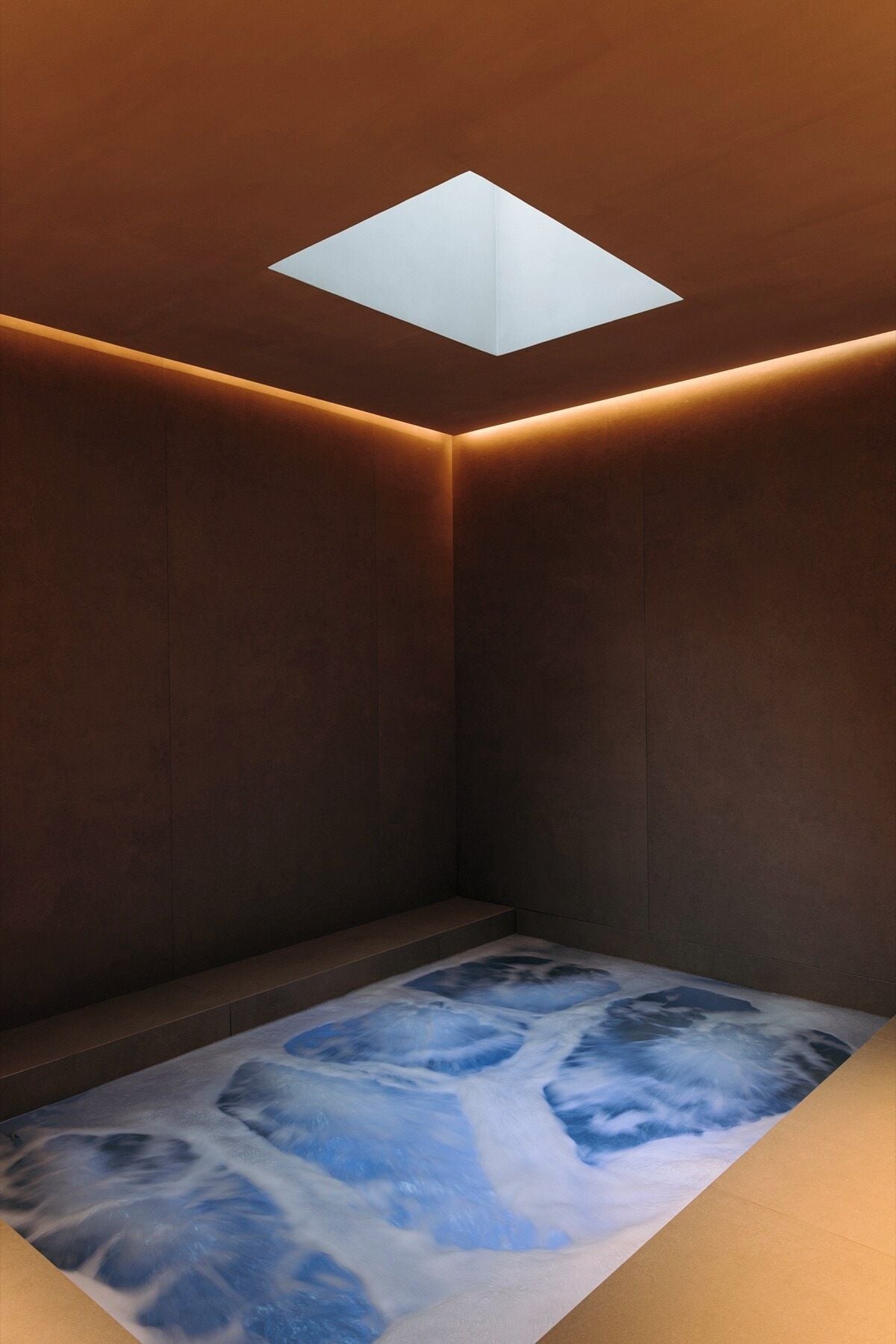 A room with a skylight, dark wooden walls, and a floor with a blue and white pattern.