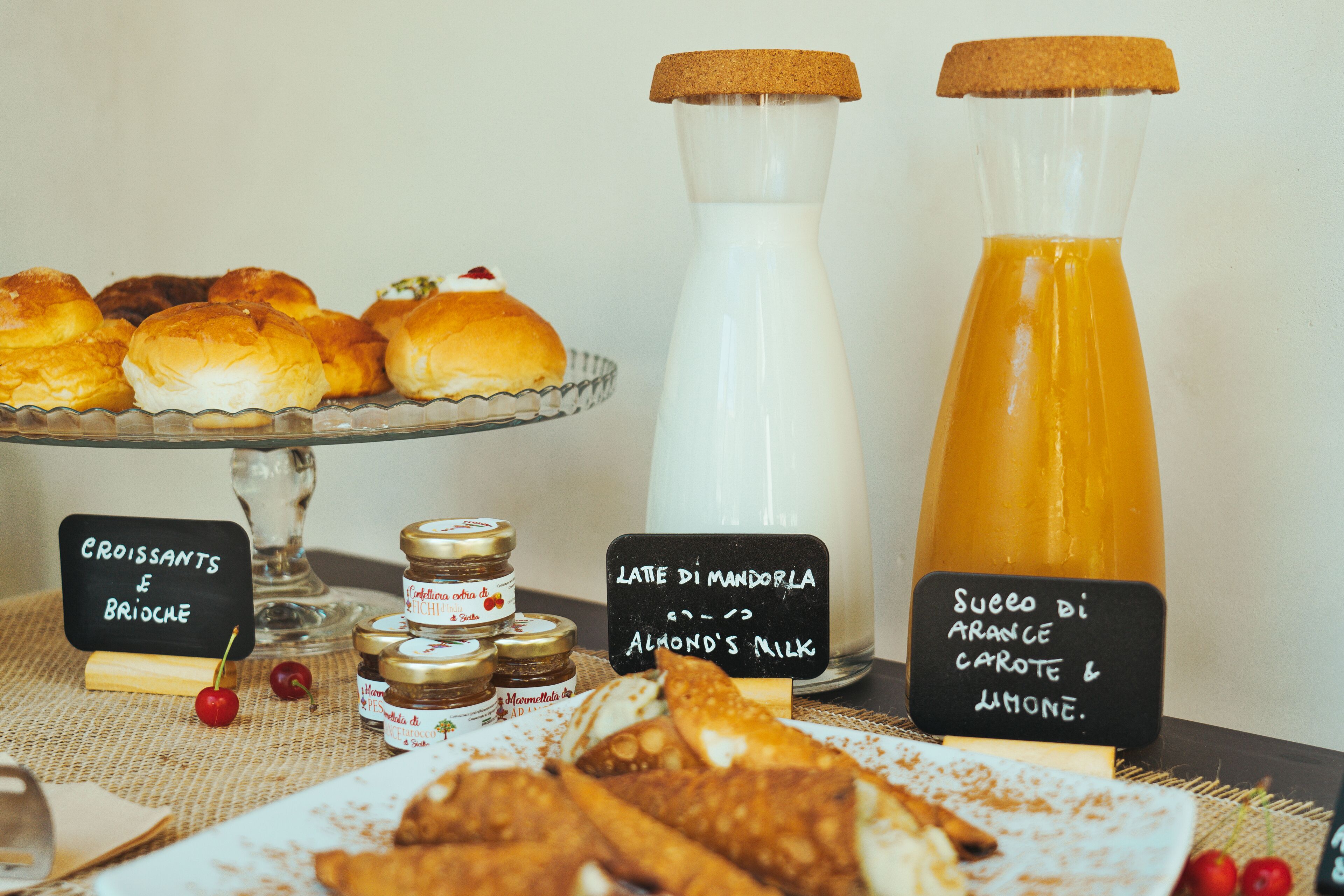 A breakfast buffet with croissants, brioche, almond milk, and orange juice.