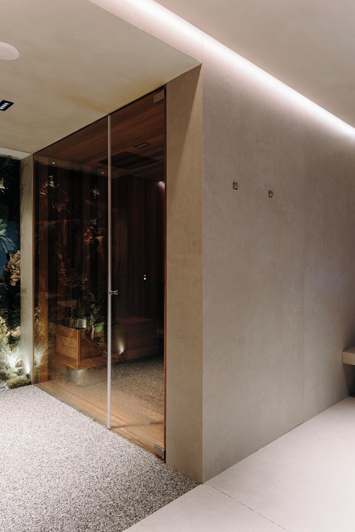 Un interior moderno con un panel de vidrio, un banco de madera y un pequeño acuario.