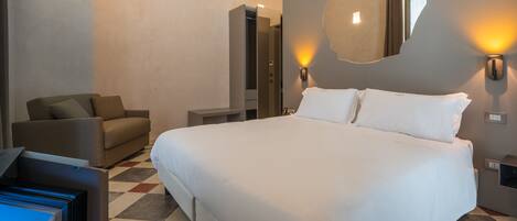 A hotel room with a large bed, a sofa, a TV, and a mirror on the wall.