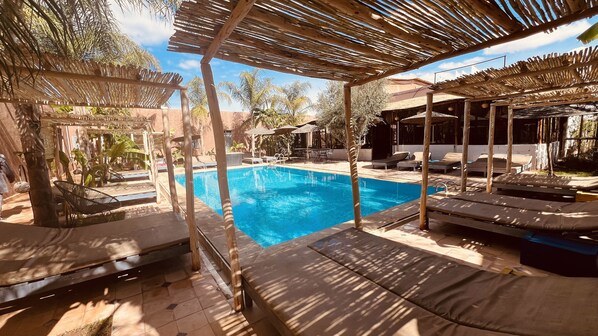 A poolside area with lounge chairs and a pergola structure.