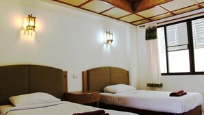 A hotel room with two beds, a wooden ceiling, and two wall-mounted lights.