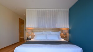 A neatly made bed with white linens, a wooden headboard, and a bedside table with a lamp. - Hotel le Tomino (Tomino)
