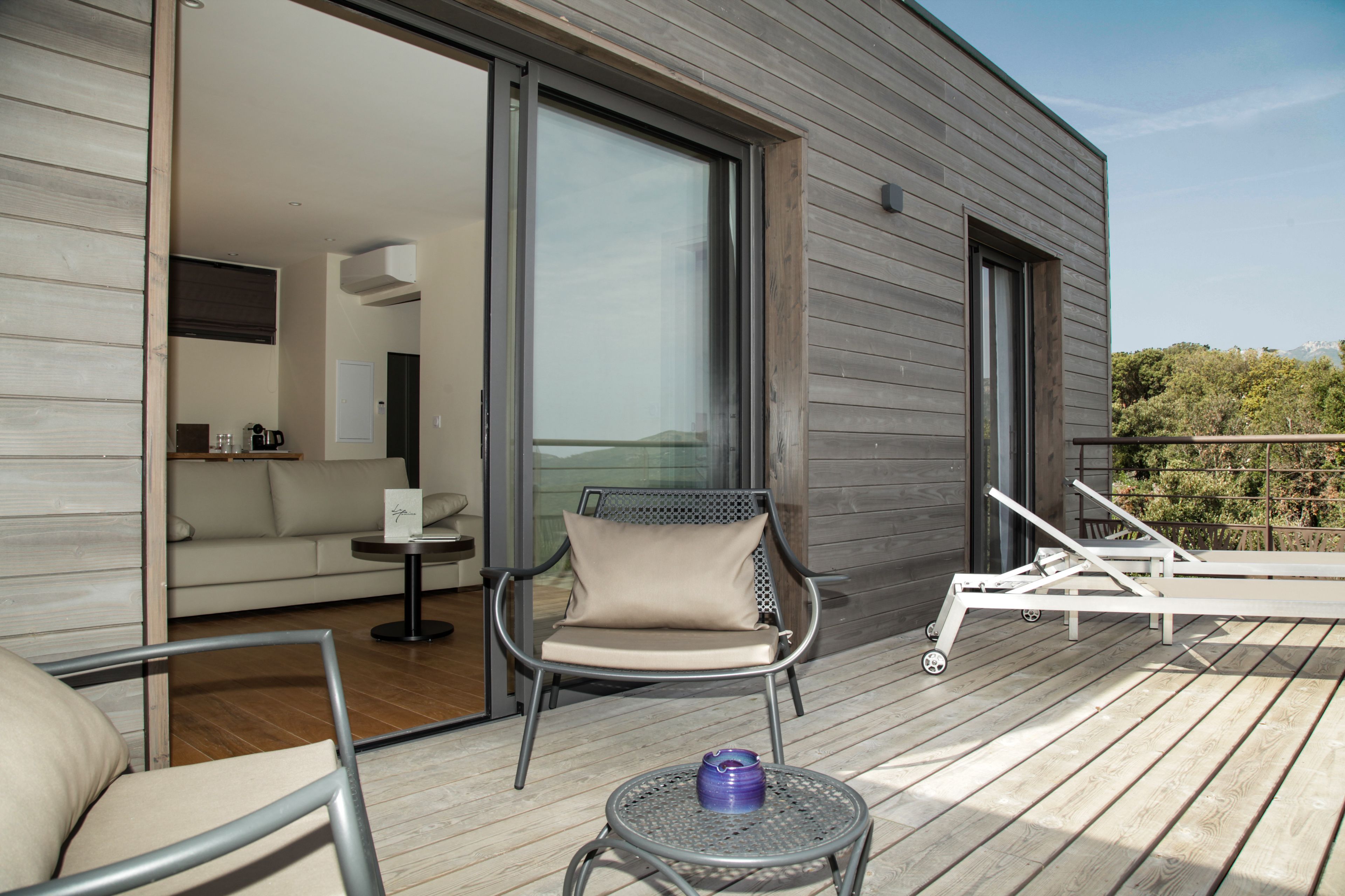 A modern outdoor deck with a sofa, a lounge chair, and a small table.
