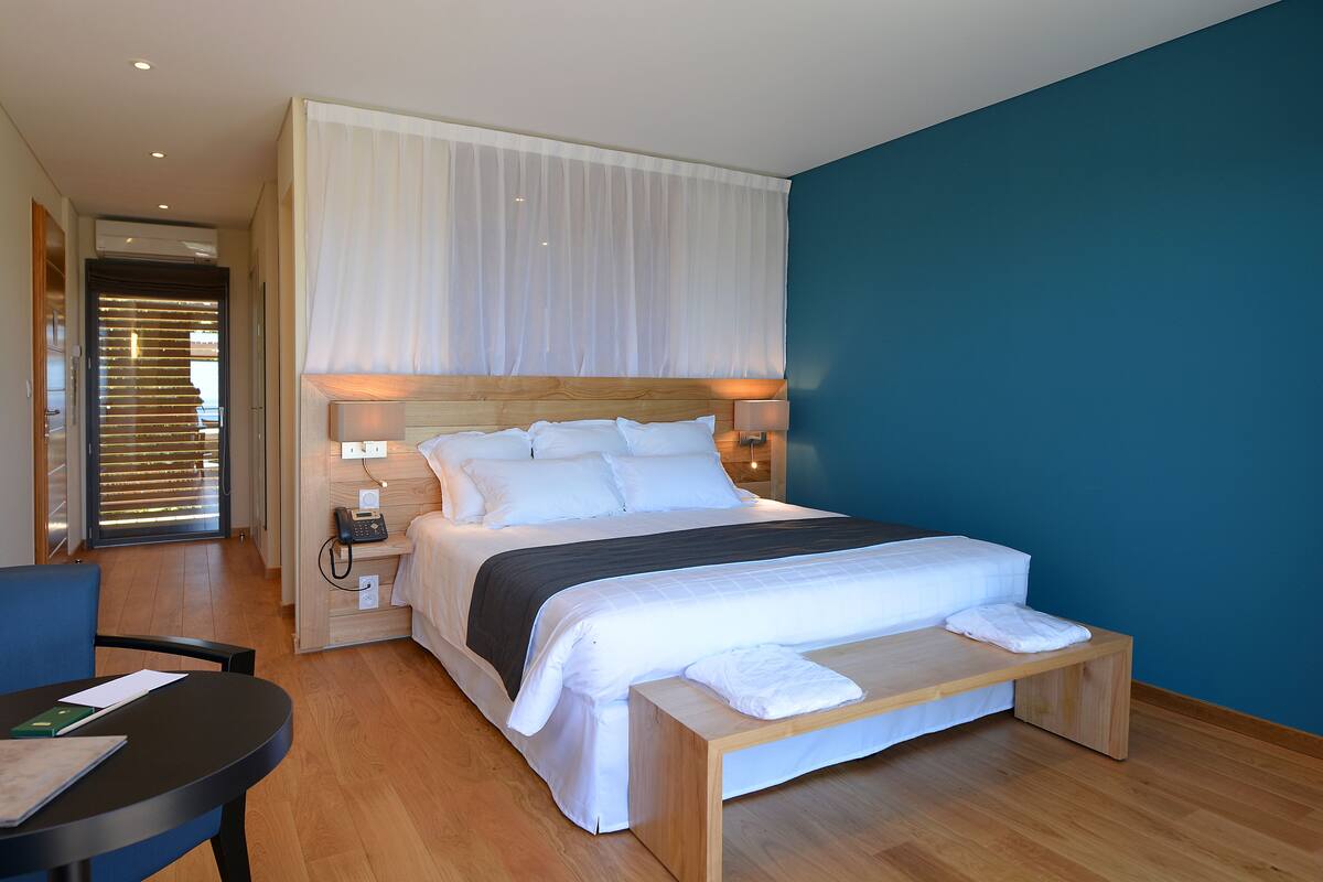 Une chambre d’hôtel moderne, dotée d’un grand lit, de tables de chevet, d’un bureau et d’une chaise.