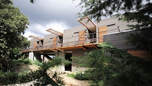 A modern multi-story building with a flat roof, wooden balconies, and a landscaped garden area. - Hotel le Tomino (Tomino)