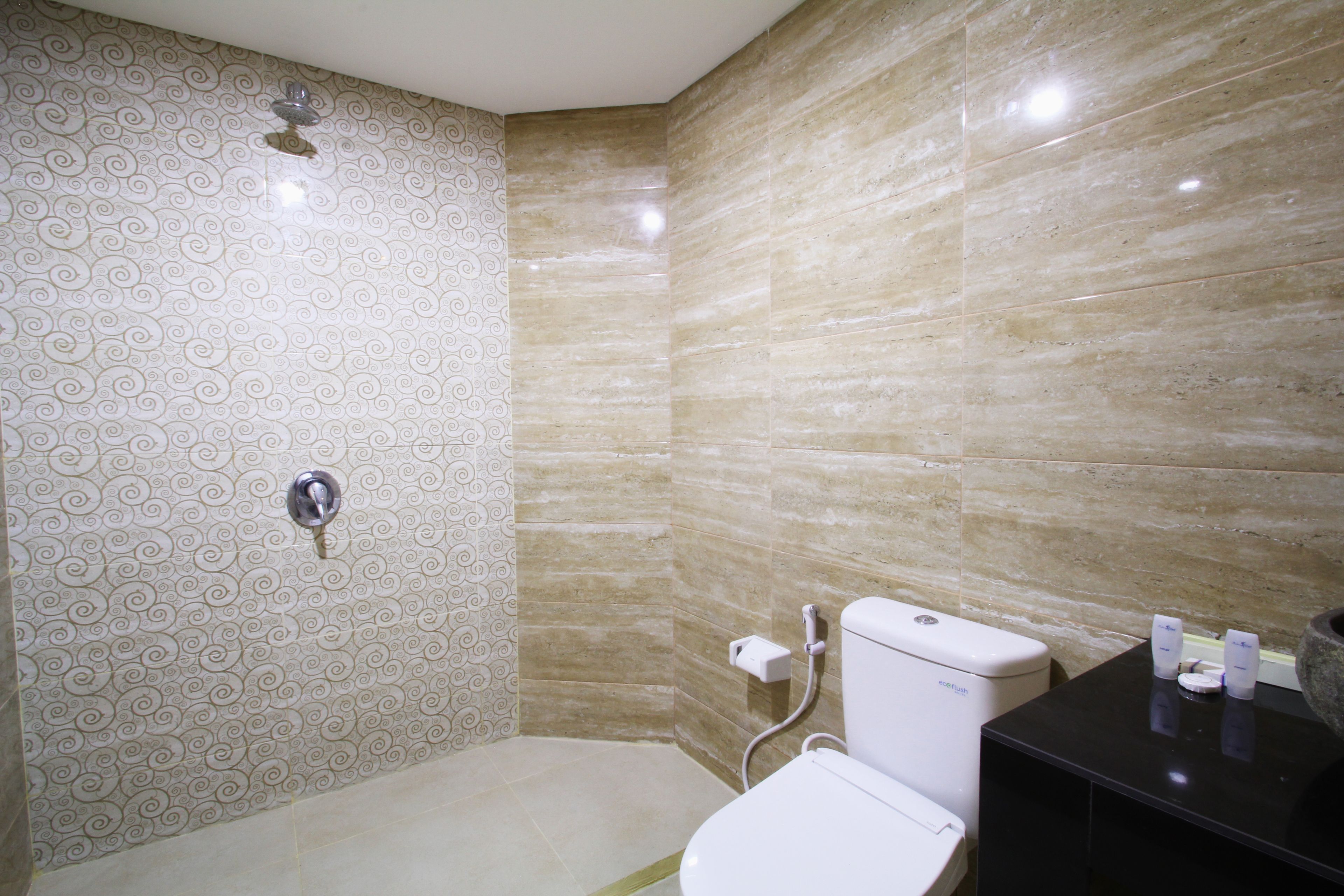 A bathroom with patterned walls, a toilet, a shower, and a black countertop with toiletries.