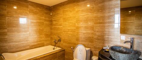 A modern bathroom with a bathtub, toilet, and a large sink.