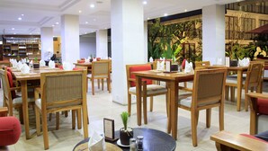 A restaurant with wooden tables and chairs, potted plants, and a large indoor plant wall. - Bakung Ubud Resort and Villa (Ubud)