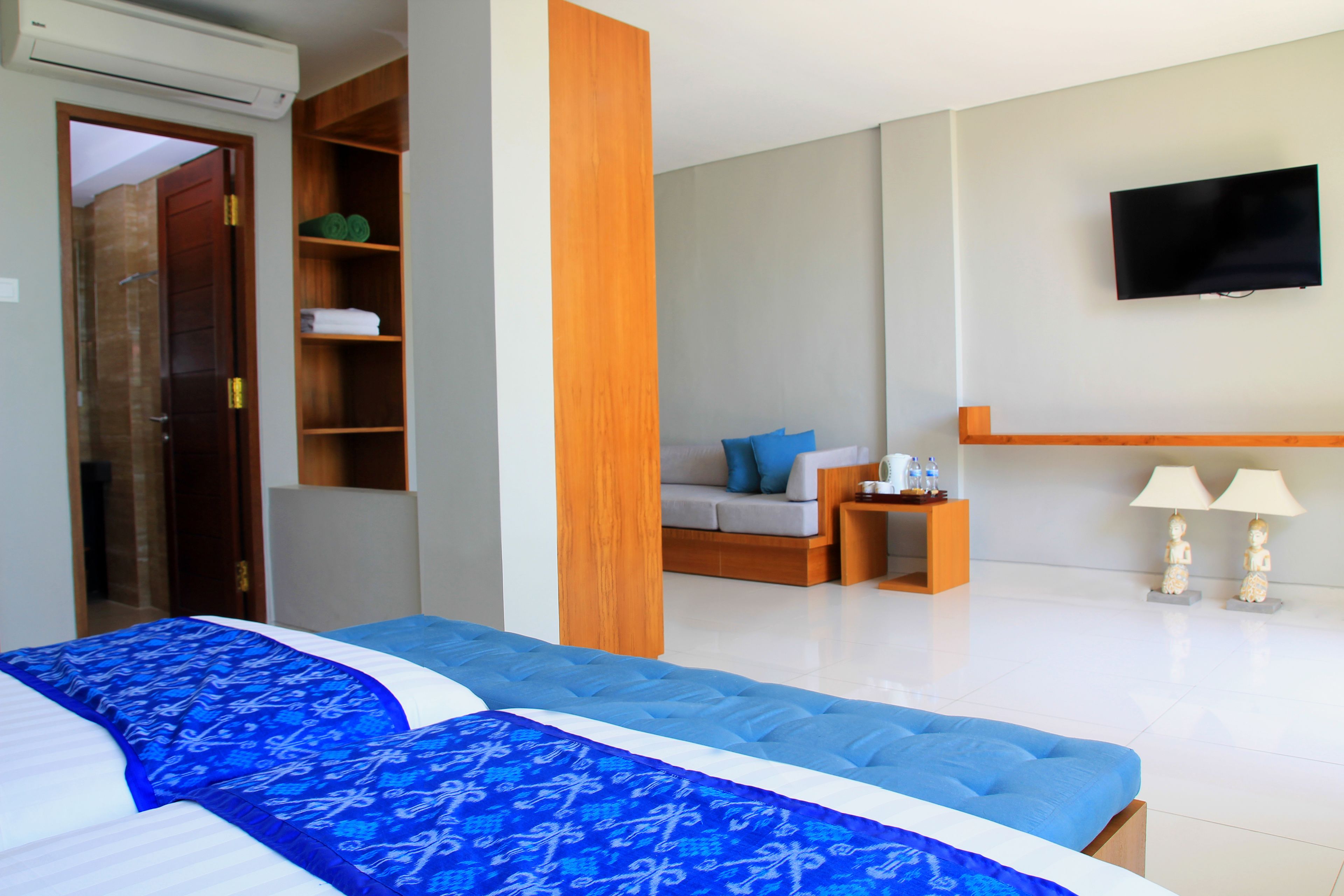 A hotel room with a large bed, a sofa, a TV, and a bathroom with a shower and toilet.