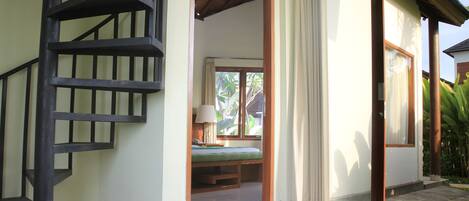 A staircase leading to a bedroom with a bed, a window, and a view of greenery outside.