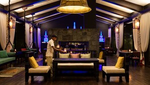 A spacious lounge area with a high ceiling, a bar in the center, and a person standing by the bar. - The Pavilions Himalayas The Farm (Pokhara)