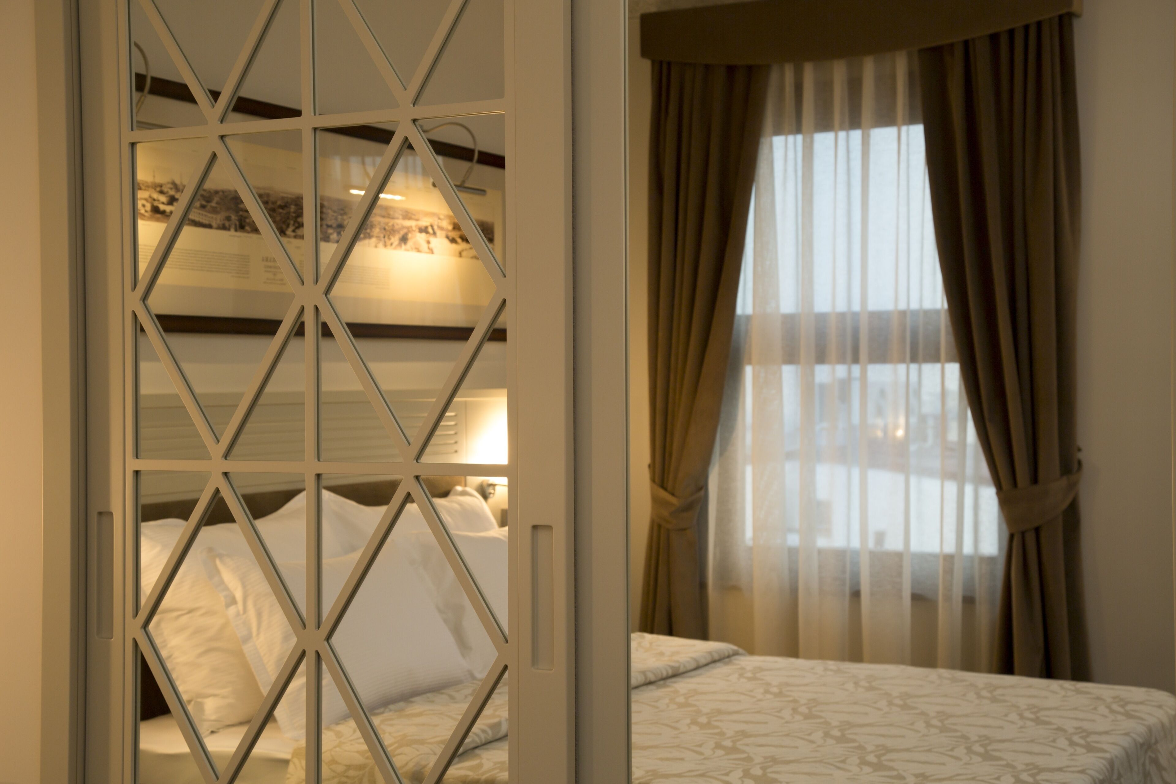 A hotel room with a bed, a window with curtains, and a view of the cityscape.