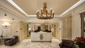 A reception area with a chandelier, reception desk, two leather chairs, and a patterned carpet. - Taxim Lounge Hotel - Special Class (Istanbul)