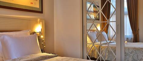 Een hotelkamer met een bed, nachtkastje, een lijst met foto aan de muur en een raam met gordijnen.