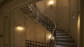A grand staircase with ornate metal railings and wall sconces providing light. - Taxim Lounge Hotel - Special Class (Istanbul)