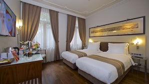 A hotel room with two beds, a desk with a vase of flowers, a clock, and a framed picture on the wall. - Taxim Lounge Hotel - Special Class (Istanbul)