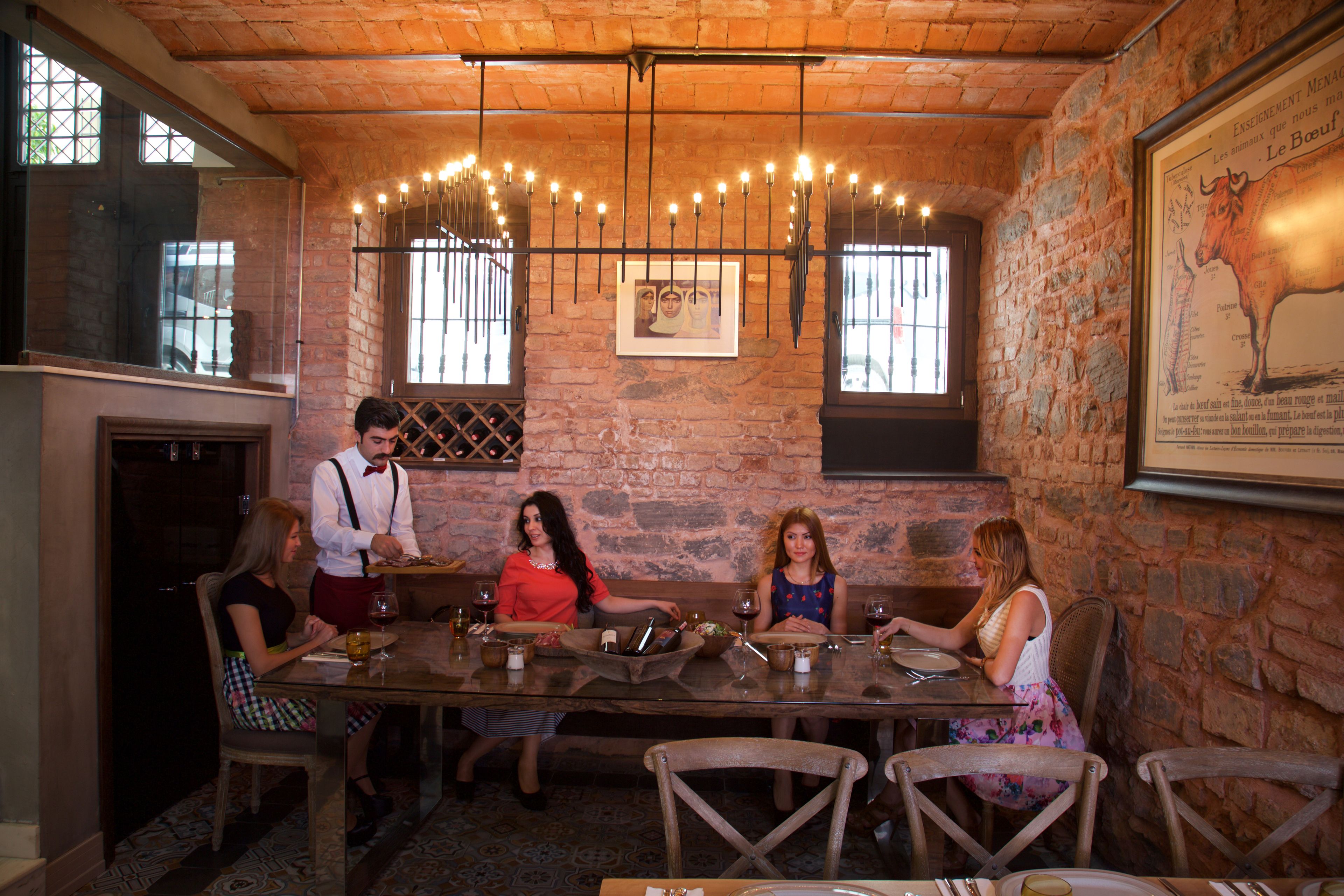 Un coin repas rustique avec un mur en briques, un plafond en bois et une longue table entourée de chaises.