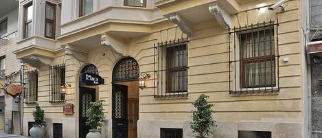 A historic building with a prominent entrance, large potted plants, and a security camera.