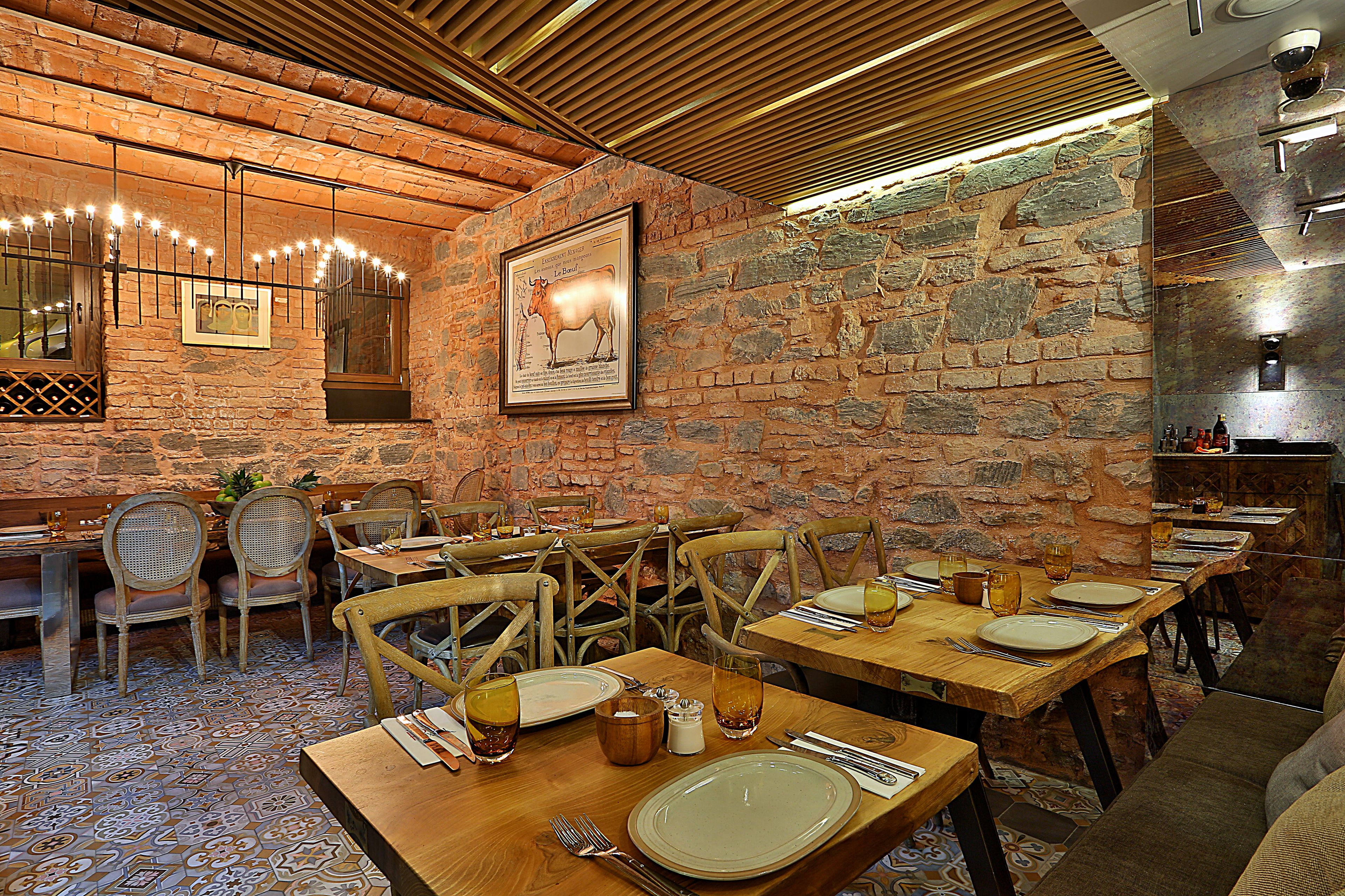 Restaurante com paredes de tijolo, mesas e cadeiras de madeira.