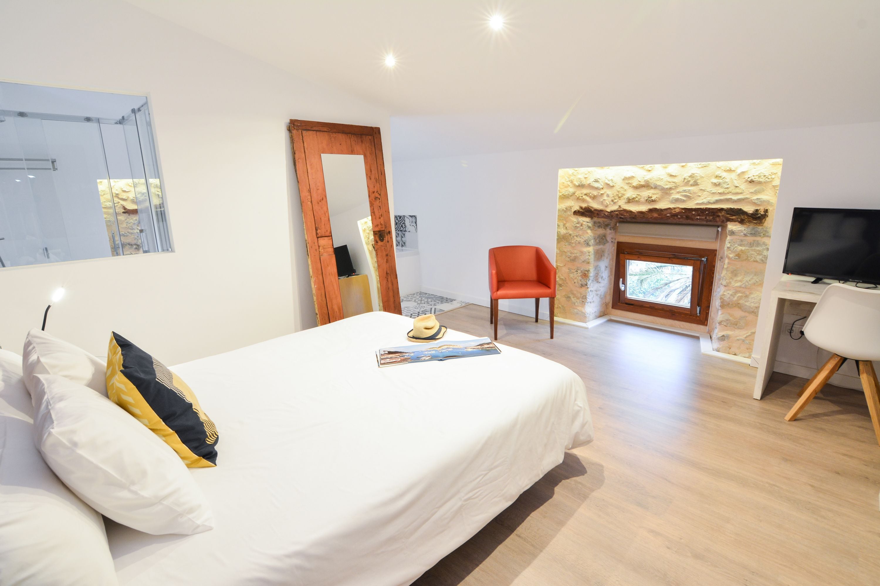 Un dormitorio con cama, una silla, televisor y chimenea.