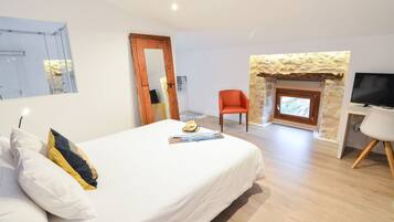 Un dormitorio con cama, una silla, televisor y chimenea.