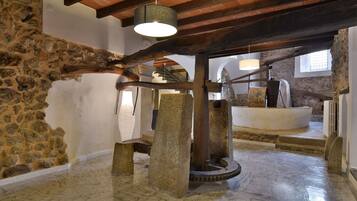 Una habitación de paredes de piedra con una gran noria y estructura de madera.