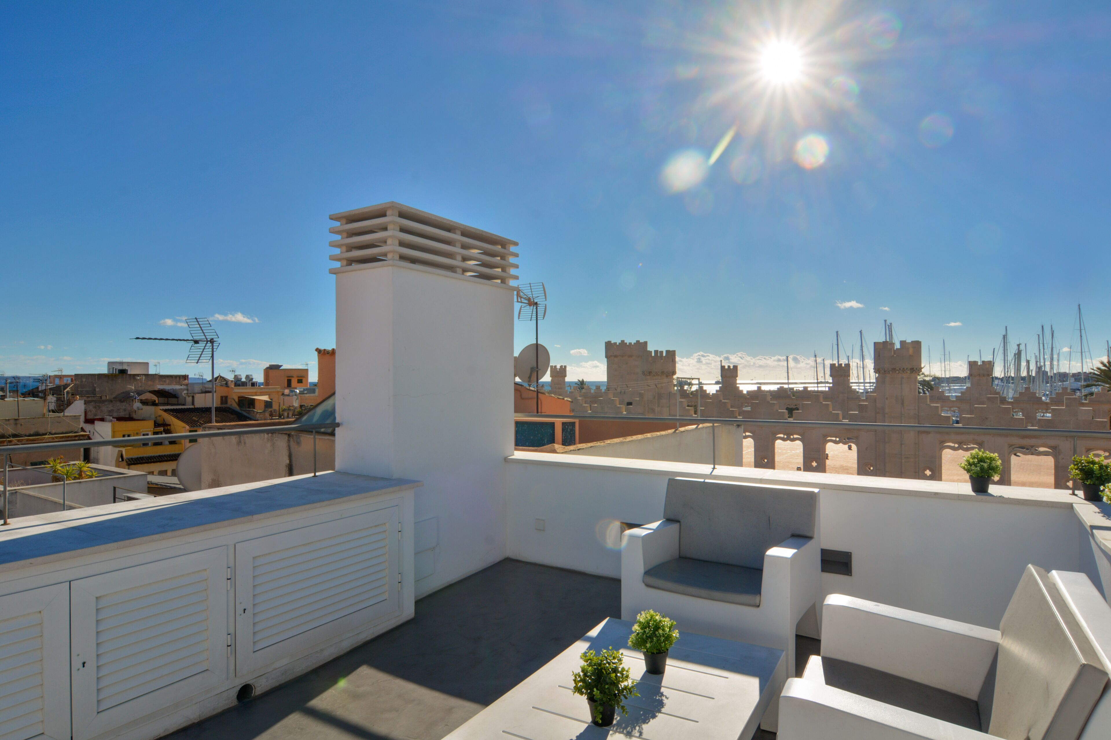 Una terrassa al terrat amb parets i sostre blancs, i una vista de l'horitzó urbà.