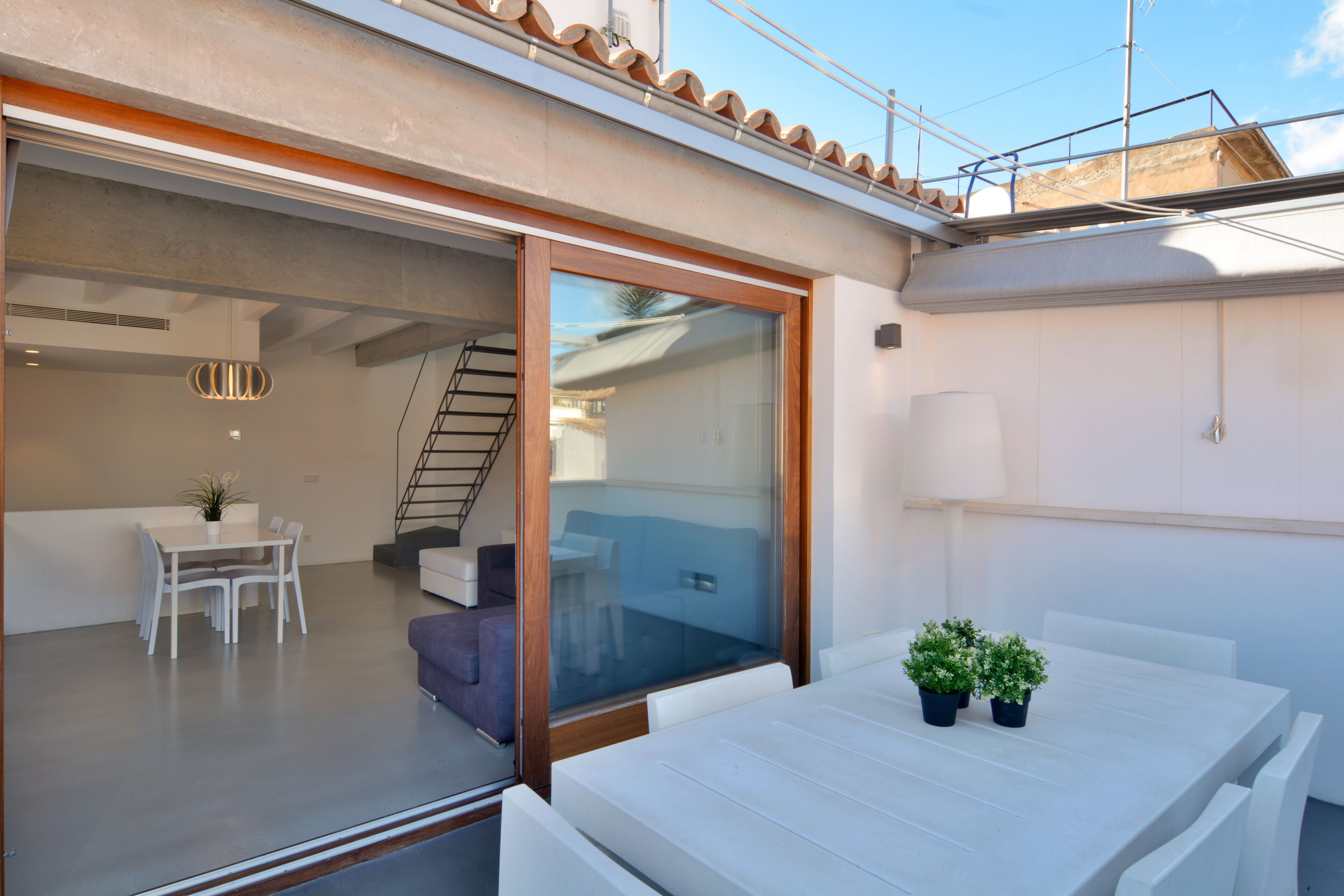 Un interior moderno con zona de comedor, escalera y puerta de vidrio que da a un espacio exterior.