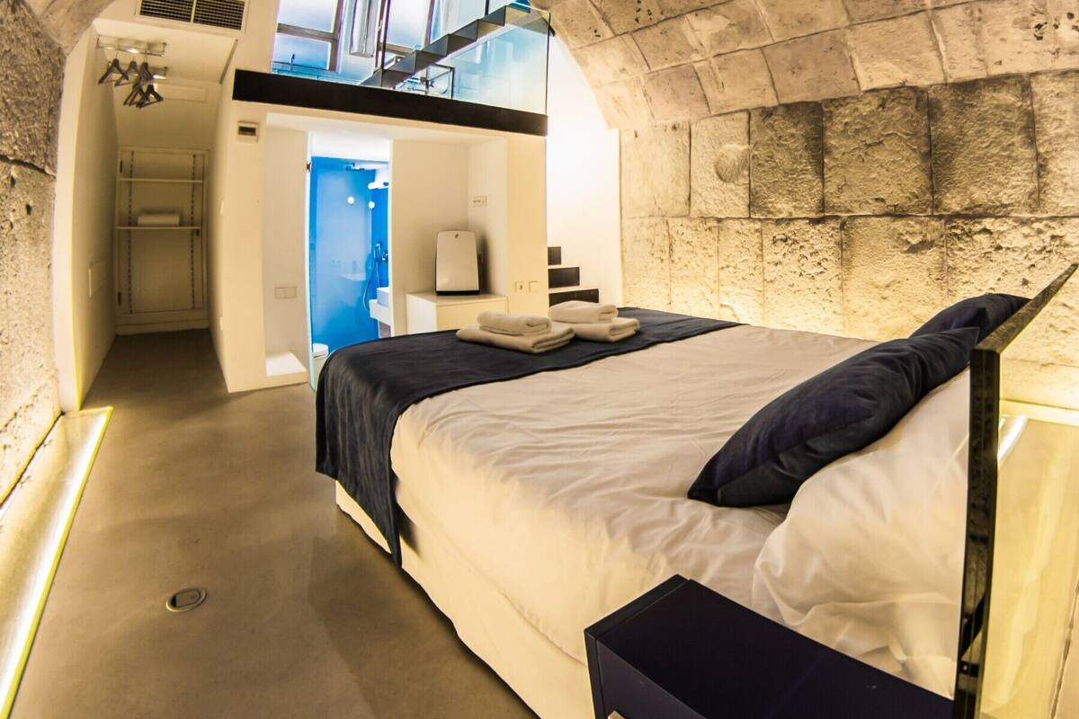 Een moderne slaapkamer met een groot bed, een inbouwkast en een zichtbare badkamer door een geopende deur.